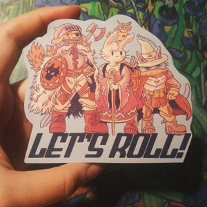 Op de afbeelding: Een sticker met een groep cartoonfiguren die verkleed zijn als avonturiers. De personages zijn een hond, een konijn en een kat. De sticker heeft de tekst "Let's Roll!" erop gedrukt.