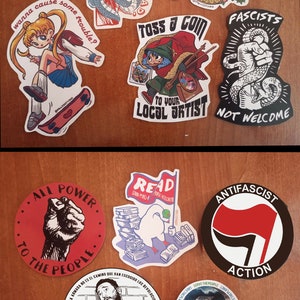 May include: Two sets of stickers, labeled "Bundle 17" and "Bundle 18". Bundle 17 includes stickers with images of a snake, a knife, a cartoon girl, a cartoon elf, and a fist with a snake. Bundle 18 includes stickers with images of a fist, a stack of books, a fist with a red flag, a man with a beard, and a blue wave.
