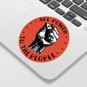 Puede incluir: Un círculo rojo con un puño negro levantado y el texto "ALL POWER TO THE PEOPLE." en una fuente negra manuscrita.
