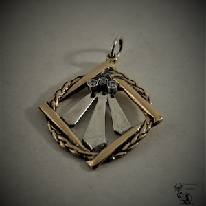 May include: A two-tone pendant with a silver and gold design. The pendant features a square frame with a braided texture, and a central design of three silver rays, each with a small, clear gemstone. The pendant has a silver bail.