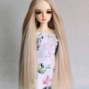 Puede incluir: Una peluca larga, recta y rubia clara para una muñeca. La peluca está hecha de cabello sintético y tiene un acabado de aspecto natural.