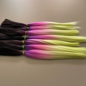 May include: Six strands of ombre hair extensions in black, purple, pink, and yellow.