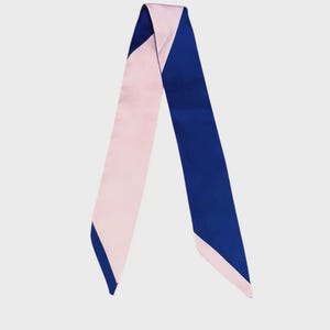 May include: A two-toned silk scarf in a diagonal design. One side is a soft pink, and the other is a deep blue. The scarf has a sleek, elegant appearance, suitable for various styling options.
