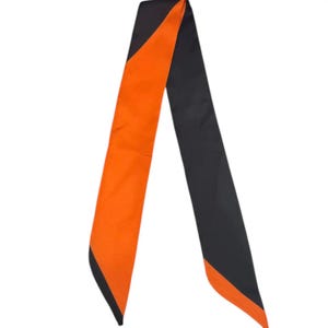 May include: A long, narrow scarf with a striking color-block design. One side is a vibrant orange, while the other is a deep black. The scarf's ends are finished with a contrasting black trim, adding a touch of elegance. This accessory is suitable for various styling options.