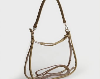 Può includere: Una borsa trasparente con una tracolla marrone e una tracolla marrone più piccola e staccabile. La borsa ha una cerniera e finiture color oro e hardware in metallo color argento. La borsa è progettata per essere indossata a spalla o a mano.