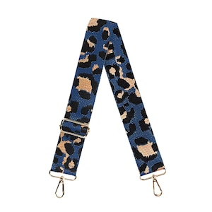May include: A blue and tan leopard print bag strap with gold-colored metal hardware. The strap features a repeating pattern of black and tan leopard spots on a blue background. The strap has gold-colored metal clasps on each end.