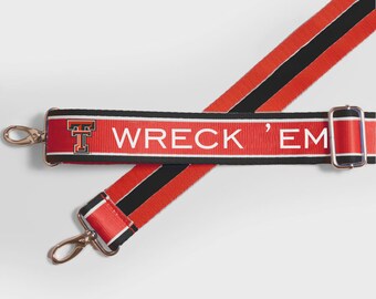 May include: Red and black striped shoulder strap with the text "WRECK 'EM" in white. The strap has gold-colored metal clasps and a buckle. The strap features the letter "T" in a red and black design.