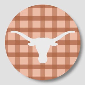 May include: A circular sticker featuring a white silhouette of a longhorn steer head centered against a background of light peach and muted brown plaid pattern. The design is flat and graphic, showcasing the iconic wide horns of the animal.