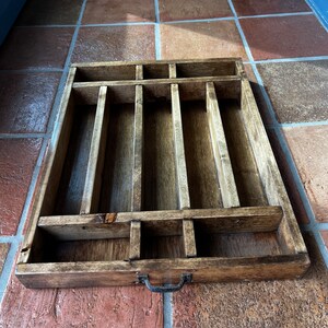 May include: A wooden cutlery tray with multiple compartments for organizing silverware. The tray has a dark brown stain and a metal handle.