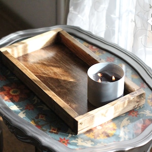May include: A wooden tray with a gray candle in the center. The tray is on a table with a floral pattern. The text "GREY RIVER Market" is visible in the top right corner of the image.