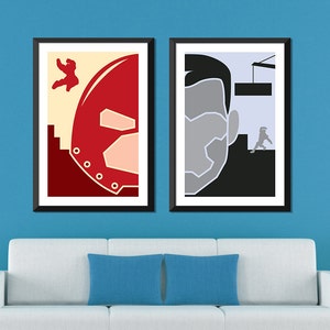 May include: Two minimalist posters with a red and white helmet on the left and a gray head with a black background on the right. The posters are framed in black and hanging on a blue wall.