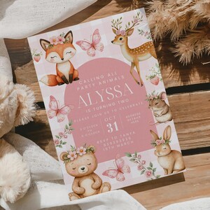 以下が含まれることがあります： 「CALLING ALL PARTY ANIMALS」と「ALYSSA IS TURNING TWO」の文字が入ったピンクと白の招待状。キツネ、シカ、ネズミ、ウサギ、クマ、蝶のイラストが特徴です。