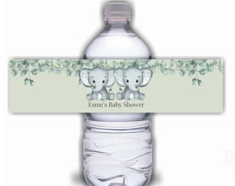 May include: Water bottle label with two gray elephants and green leaves. The label reads "Esmé's Baby Shower".