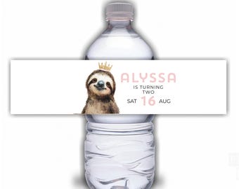 May include: A clear water bottle with a custom label featuring a cartoon sloth wearing a gold crown. The label reads "Alyssa is turning two" and the date "16 Aug". The sloth has a smiling expression.
