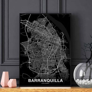May include: Black and white city map print of Barranquilla, Colombia. The map is framed in a black frame and is displayed on a shelf with a vase and decorative objects.