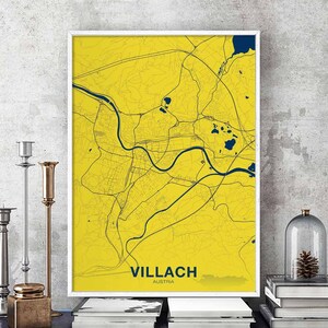 May include: A yellow and blue map print of Villach, Austria. The map shows the city's streets and waterways. The city name is printed in bold at the bottom of the map.