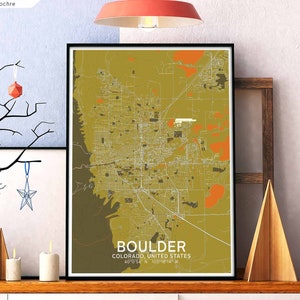 Può includere: Una mappa incorniciata di Boulder, Colorado, in uno schema di colori oro e ocra. La mappa mostra le strade e i punti di riferimento della città. Il testo "BOULDER, COLORADO, UNITED STATES" e le coordinate "40°0'54" N 105°10'14" W" sono stampate sotto la mappa.