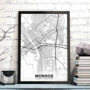 May include: Black and white map print of Monroe, Louisiana, in a black frame. The map shows the city streets and waterways. The print is on a white background.