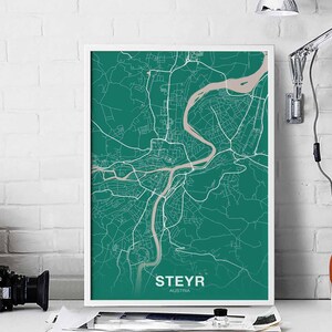 May include: A teal green city map print with white lines showing the streets of Steyr, Austria. The print is framed in a white frame.