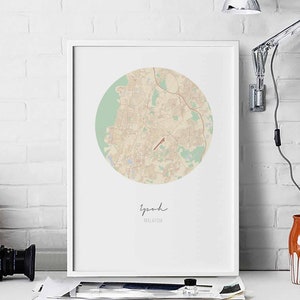 Pode incluir: Uma impressão emoldurada branca de um mapa de Ipoh, Malásia. O mapa está em um círculo com um fundo verde claro e linhas marrons. O nome da cidade está escrito em itálico abaixo do mapa.