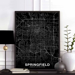 Pode incluir: Impressão de mapa da cidade de Springfield, Missouri, Estados Unidos, em preto e branco. O mapa está emoldurado em uma moldura preta e é exibido em uma prateleira com uma lâmpada preta e um vaso branco.