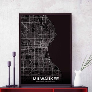 May include: Black and white city map print of Milwaukee, Wisconsin, United States. The map is framed in a black frame and is hanging on a white wall.