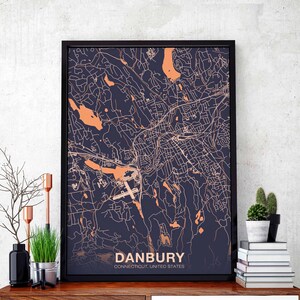 May include: A framed map of Danbury, Connecticut, with a navy blue background and orange lines depicting the city streets. The city name is printed in white at the bottom of the map.