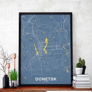 Puede incluir: Un mapa enmarcado de Donetsk, Ucrania, con un fondo azul y líneas amarillas que representan las calles. El nombre de la ciudad está impreso en blanco en la parte inferior del mapa.