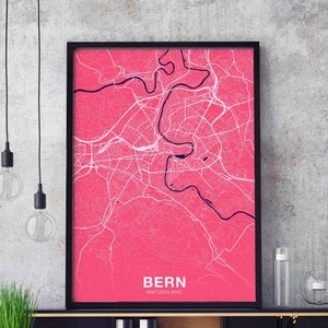May include: A pink and white city map print with a black frame. The map shows the city of Bern, Switzerland. The text "BERN SWITZERLAND" is printed at the bottom of the map.