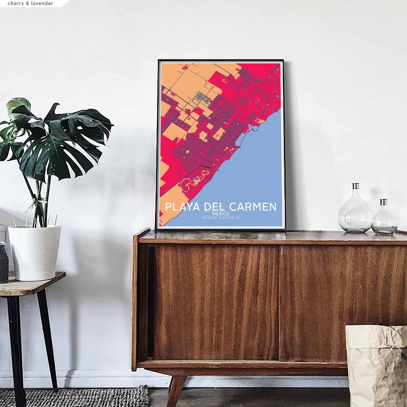 Puede incluir: Una impresi&oacute;n de mapa colorido de Playa del Carmen, M&eacute;xico, en un marco negro, colgado en una pared blanca sobre un gabinete de madera. El mapa est&aacute; en tonos de rojo, naranja y azul.