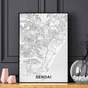 Puede incluir: Impresión en blanco y negro de un mapa de la ciudad de Sendai, Japón, en un marco negro. La impresión está sobre un fondo blanco e incluye el nombre de la ciudad y "Japón" en texto negro en la parte inferior.