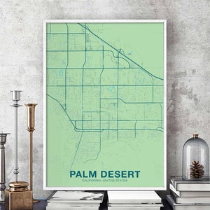 May include: A green and blue map print of Palm Desert, California, United States. The map is framed in a white frame and is hanging on a grey wall.