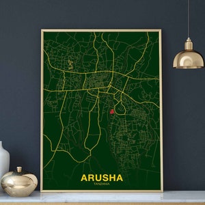 May include: A green and gold map print of Arusha, Tanzania. The map shows the city streets and roads in gold against a dark green background. The city name is printed in gold at the bottom of the map.