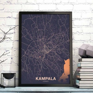 May include: A black framed print of a map of Kampala, Uganda. The map is in a dark blue colour with orange lines showing the streets. The text "Kampala, Uganda" is printed in white at the bottom of the map.
