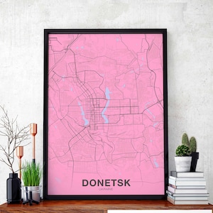 Puede incluir: Un mapa de Donetsk, Ucrania, enmarcado en negro, con fondo rosa y líneas negras que muestran las calles de la ciudad. El nombre de la ciudad está impreso en blanco en la parte inferior del mapa.