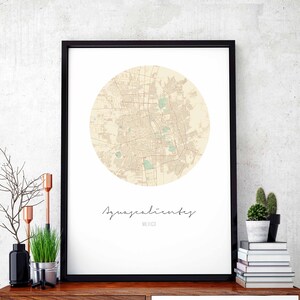 May include: A black framed print of a map of Aguascalientes, Mexico. The map is in a circle and is beige with green accents. The city name is written in cursive below the map.
