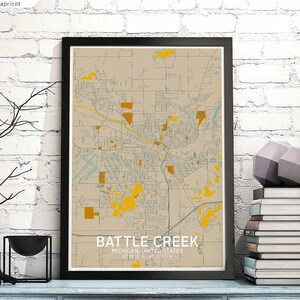 Peut inclure: Une impression encadrée d'une carte de Battle Creek, Michigan, dans une palette de couleurs neutres avec des accents de beige, de jaune et de turquoise. La carte de la ville est détaillée, montrant les rues et les points de repère. Le texte "Battle Creek, Michigan, United States" est affiché en bas.