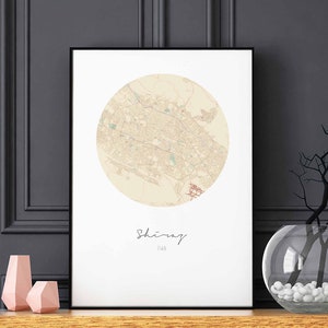 Op de afbeelding: Een zwart-witte kaartprint van de stad Shiraz, Iran, in een cirkelvormig frame. De kaart is gedrukt op een witte achtergrond met een zwarte lijst.