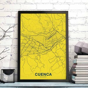 May include: A black framed print of a yellow map of Cuenca, Ecuador. The map shows the city's streets and landmarks. The text "CUENCA ECUADOR" is printed at the bottom of the map.