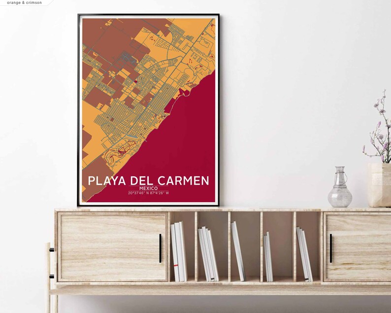 Puede incluir: Un mapa enmarcado de Playa del Carmen, M&eacute;xico, con un esquema de color rojo, naranja y amarillo. El mapa muestra las calles y los puntos de referencia de la ciudad. El texto "PLAYA DEL CARMEN" est&aacute; impreso en blanco en la parte inferior del mapa, junto con las coordenadas "20&deg;33'46" N 87&deg;4'26" W".