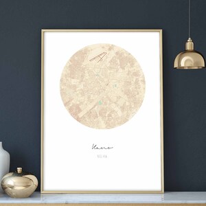 Könnte beinhalten: Eine druckbare Karte der Stadt Kaunas, Litauen, in einem kreisförmigen Design. Die Karte ist auf einem cremefarbenen Hintergrund mit braunen Linien und Text gedruckt. Der Name der Stadt ist unten auf der Karte kursiv geschrieben.