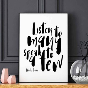 May include: Black and white typography print featuring the quote "Listen to many, speak to a few" by Mark Twain. The print is framed in a black frame and is displayed on a shelf with a vase and decorative items.