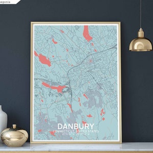 May include: A light blue and coral coloured map print of Danbury, Connecticut, United States. The map is framed in a light wood frame and is hanging on a dark blue wall.