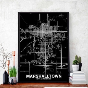 May include: Black and white map print of Marshalltown, Iowa, United States. The map is framed in a black frame and has a white background. The city streets are shown in white lines on a black background.