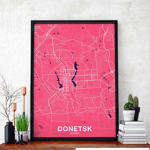 Puede incluir: Un póster enmarcado en negro con un mapa rosa de Donetsk, Ucrania. El mapa muestra las calles y los puntos de interés de la ciudad. El texto "Donetsk, Ucrania" está impreso en la parte inferior del póster.