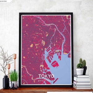Puede incluir: Un mapa enmarcado de Tokio, Japón, con un esquema de color rosa y morado. El mapa muestra las calles y los puntos de referencia de la ciudad. El texto "TOKYO" está impreso en blanco en la parte inferior del mapa.