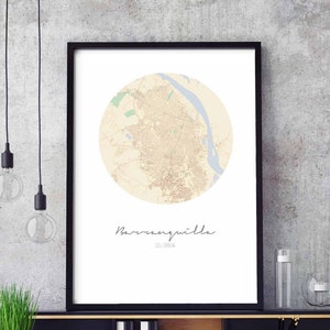May include: A black framed print of a map of Barranquilla, Colombia. The map is in a circle and is beige with brown lines. The city name is written in cursive below the map.