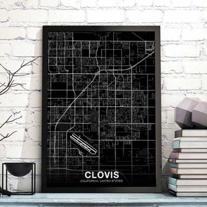 May include: A framed black and white map print of Clovis, California, with a detailed street grid and the city name at the bottom. The print is displayed on a light blue surface with decorative items.