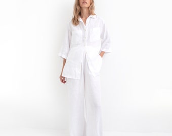 May include: A white linen shirt and pants set. The shirt has a button-up front, a collar, and two chest pockets. The pants are wide-legged and have a relaxed fit.