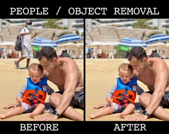 May include: A father and son are sitting on a sandy beach. The son is wearing an orange and blue life vest. The father is wearing a black swim trunk. The background is blurred and shows a beach with palm trees and umbrellas.